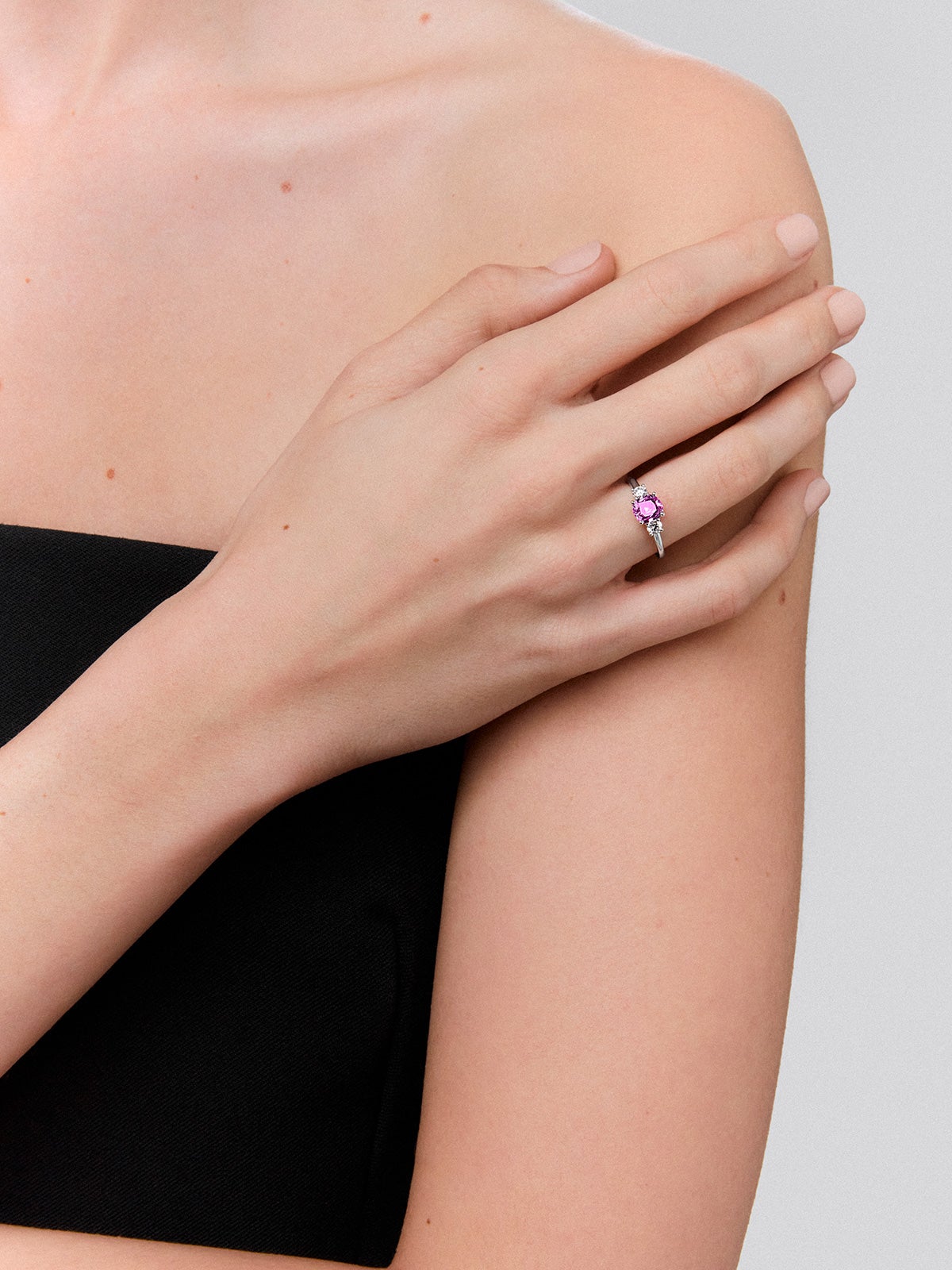 18kt white gold three-stone ring with a central 1.21cts cushion-cut pink sapphire and diamonds.