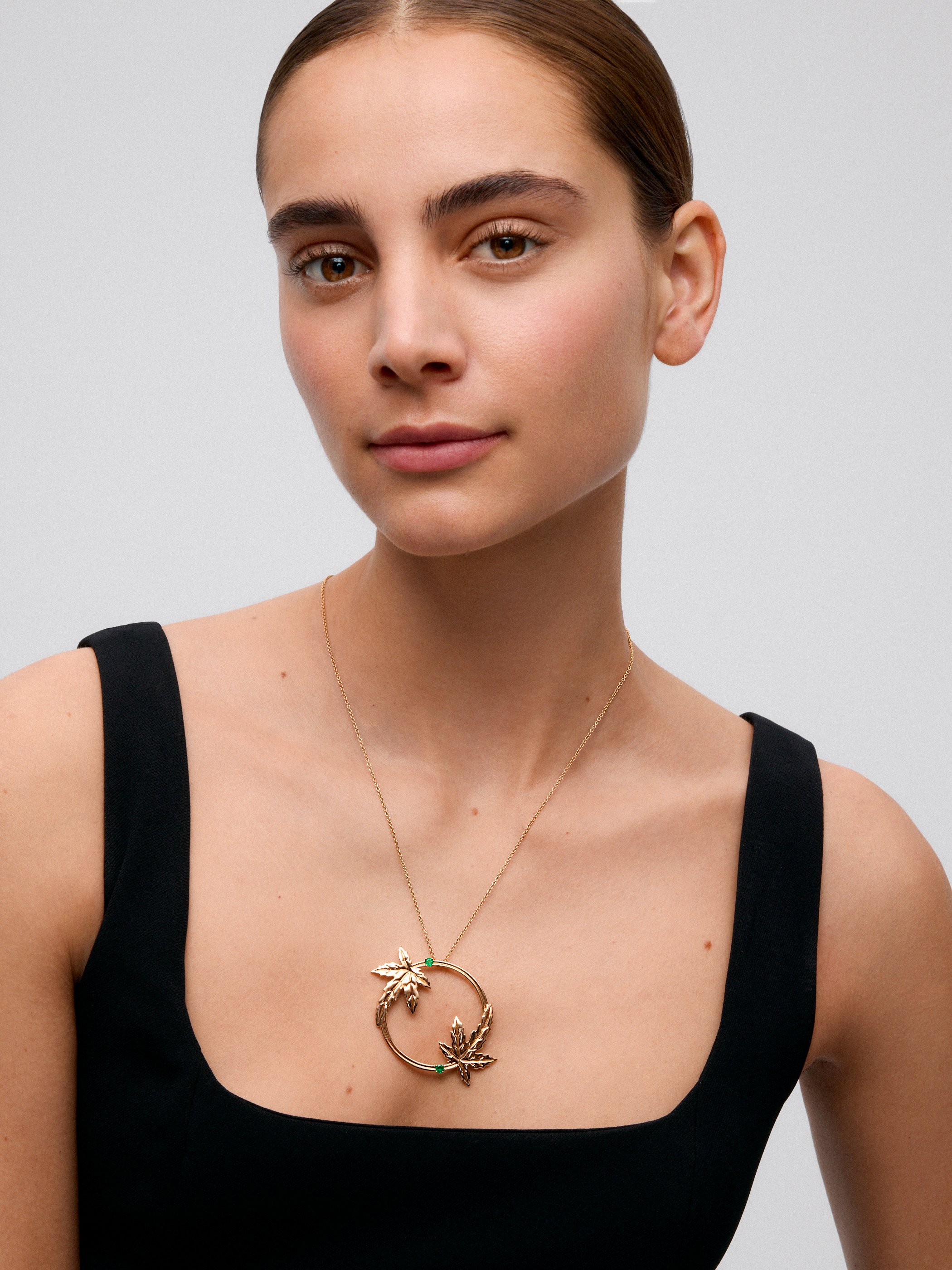 Colgante de oro amarillo de 18K con dos esmeraldas en talla brillante con un total de 0,29 cts y forma de hojas de arce