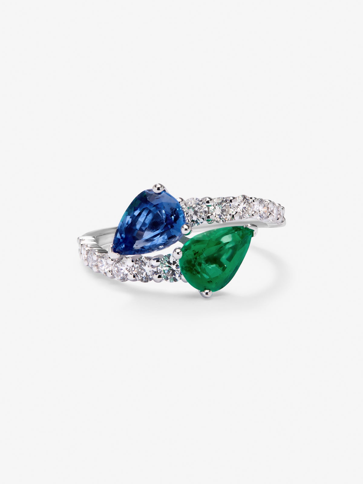 Anillo tú y yo de oro blanco de 18K con un zafiro azul intenso en talla pera de 1,49 cts, una esmeralda verde en talla pera de 1,04 cts y 14 diamantes en talla brillante con un total de 0,64 cts