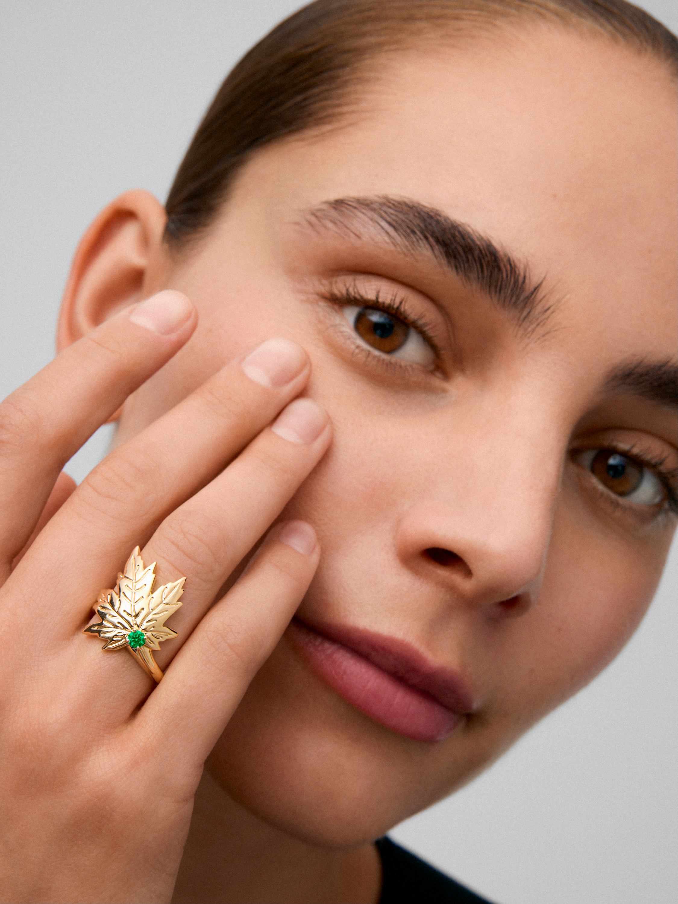 Anillo de oro amarillo de 18K con esmeralda central en talla brillante de 0,19 cts y forma de hoja de arce