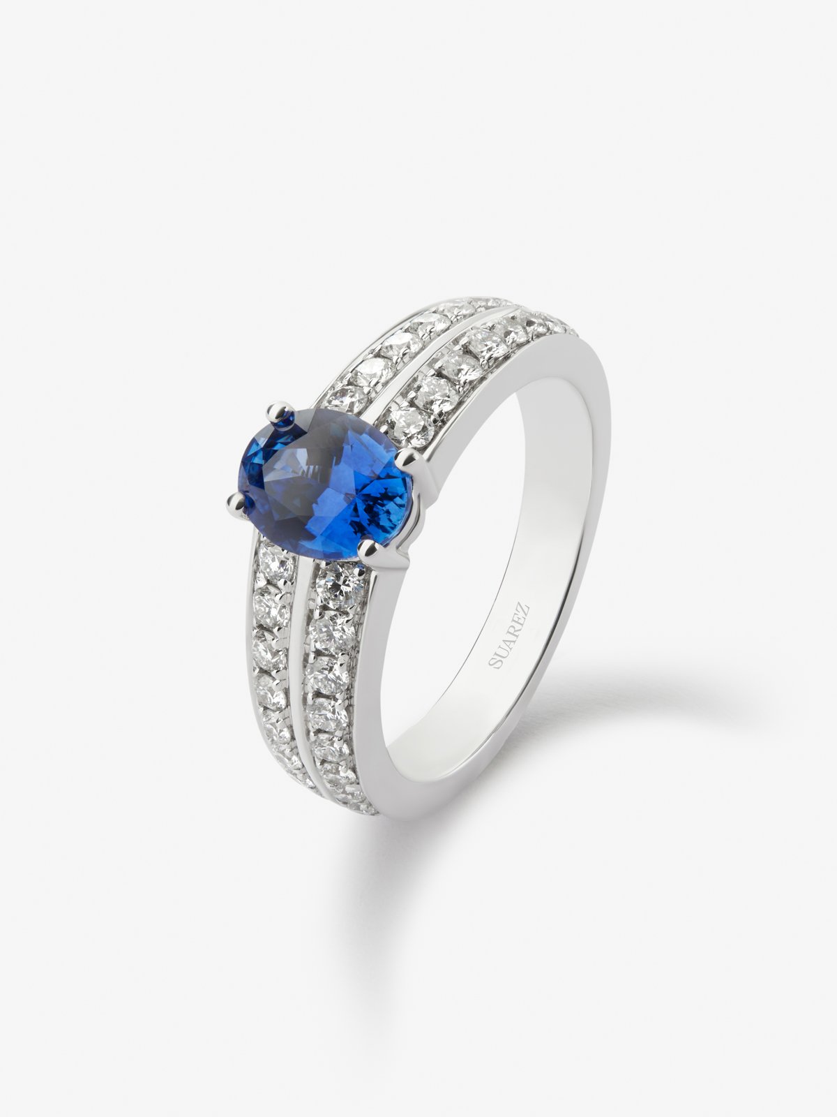 Anillo de oro blanco de 18K con zafiro azul vivid en talla oval de 1,292 cts y 32 diamantes en talla brillante con un total de 0,6 cts