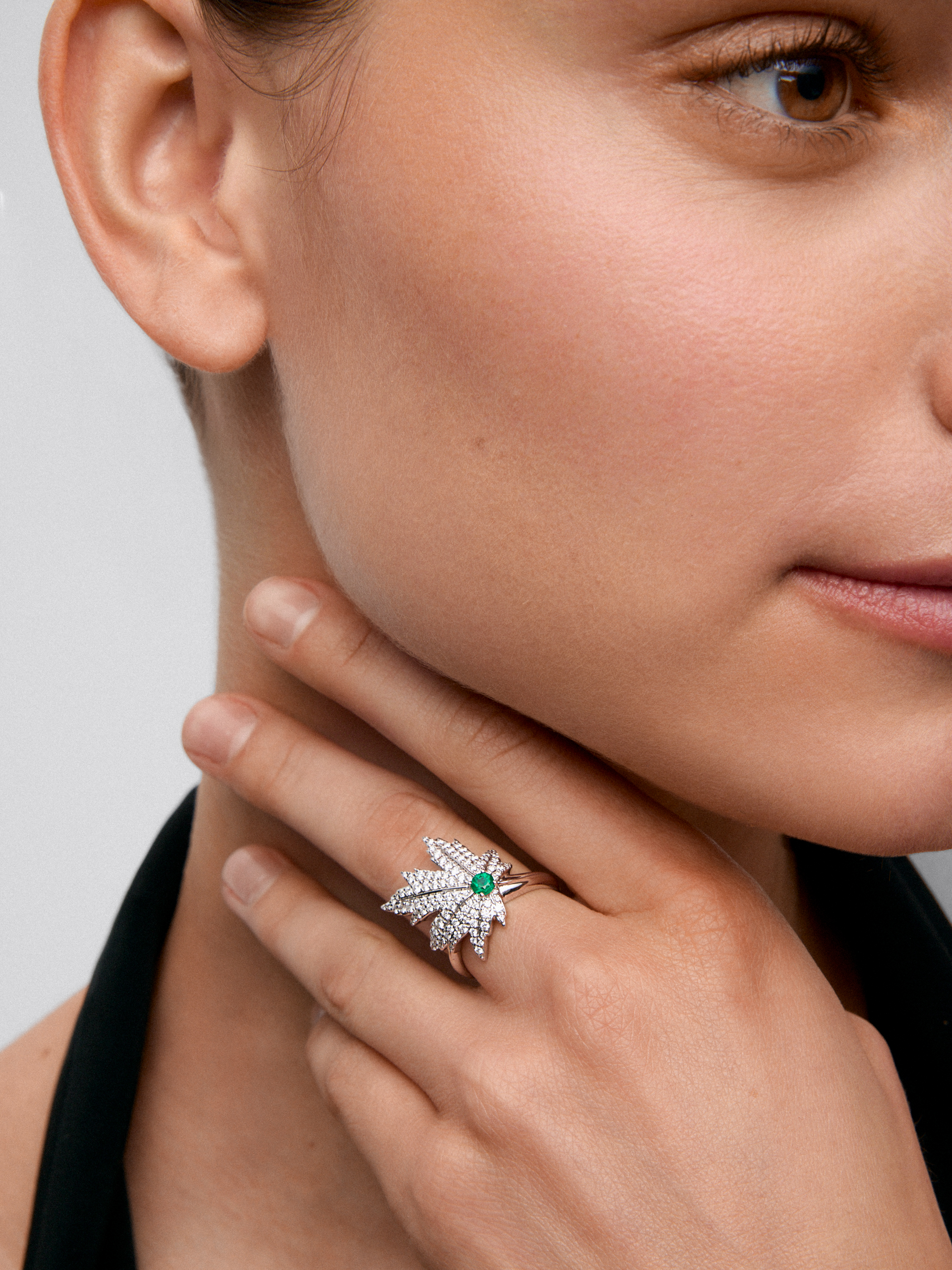 Anillo de oro blanco de 18K con esmeralda central de 0,16 cts, pavé de diamantes y forma de hoja de arce