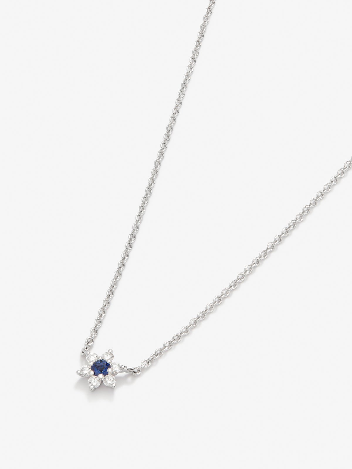 Colgante de oro blanco de 18K con zafiro azul en talla brillante de 0,1 cts y 6 diamantes en talla brillante con un total de 0,12 cts en forma de estrella