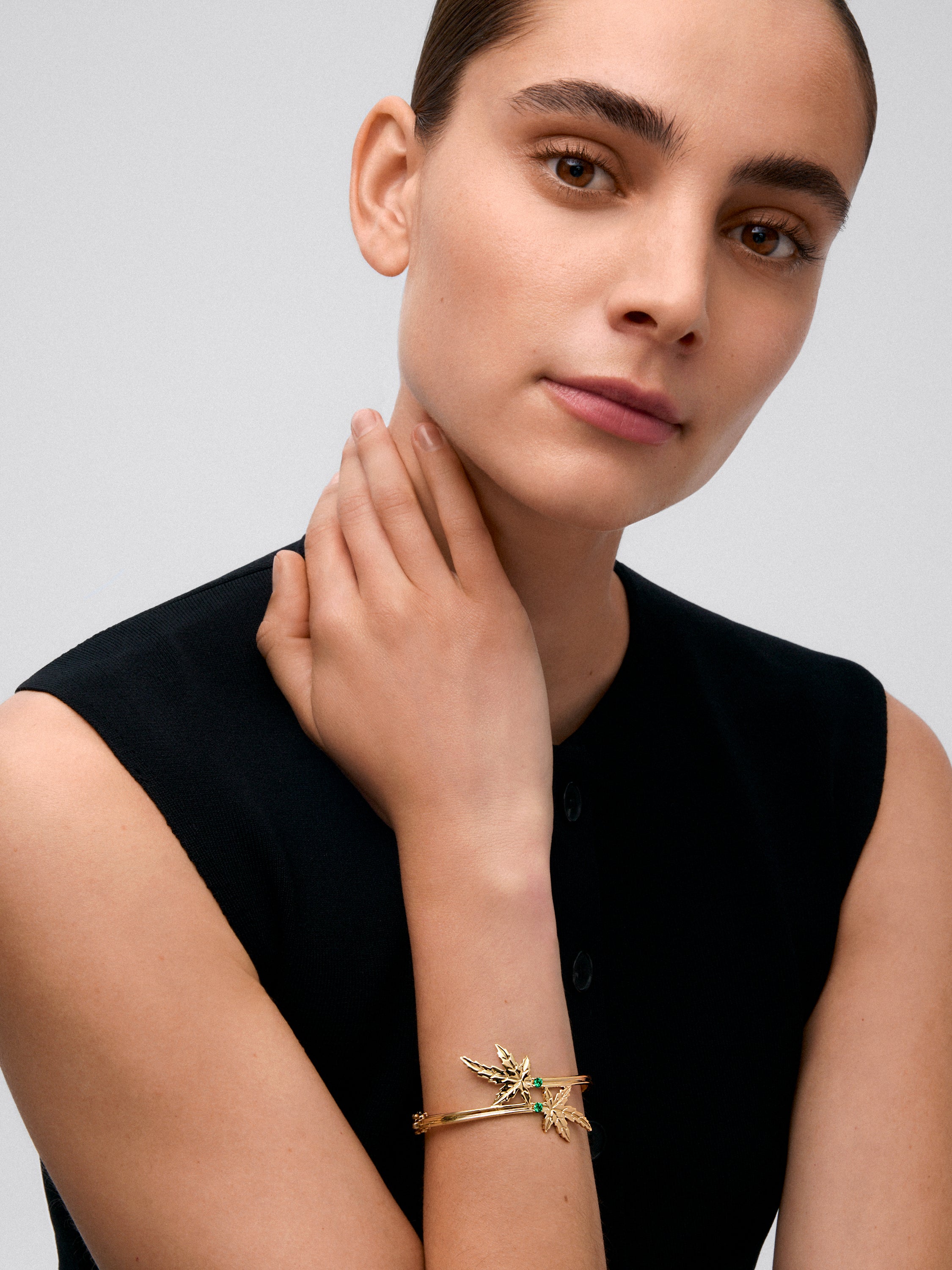 18K yellow gold bracelet with two brilliant-cut emeralds totaling 0.23 cts, in a maple leaf design.