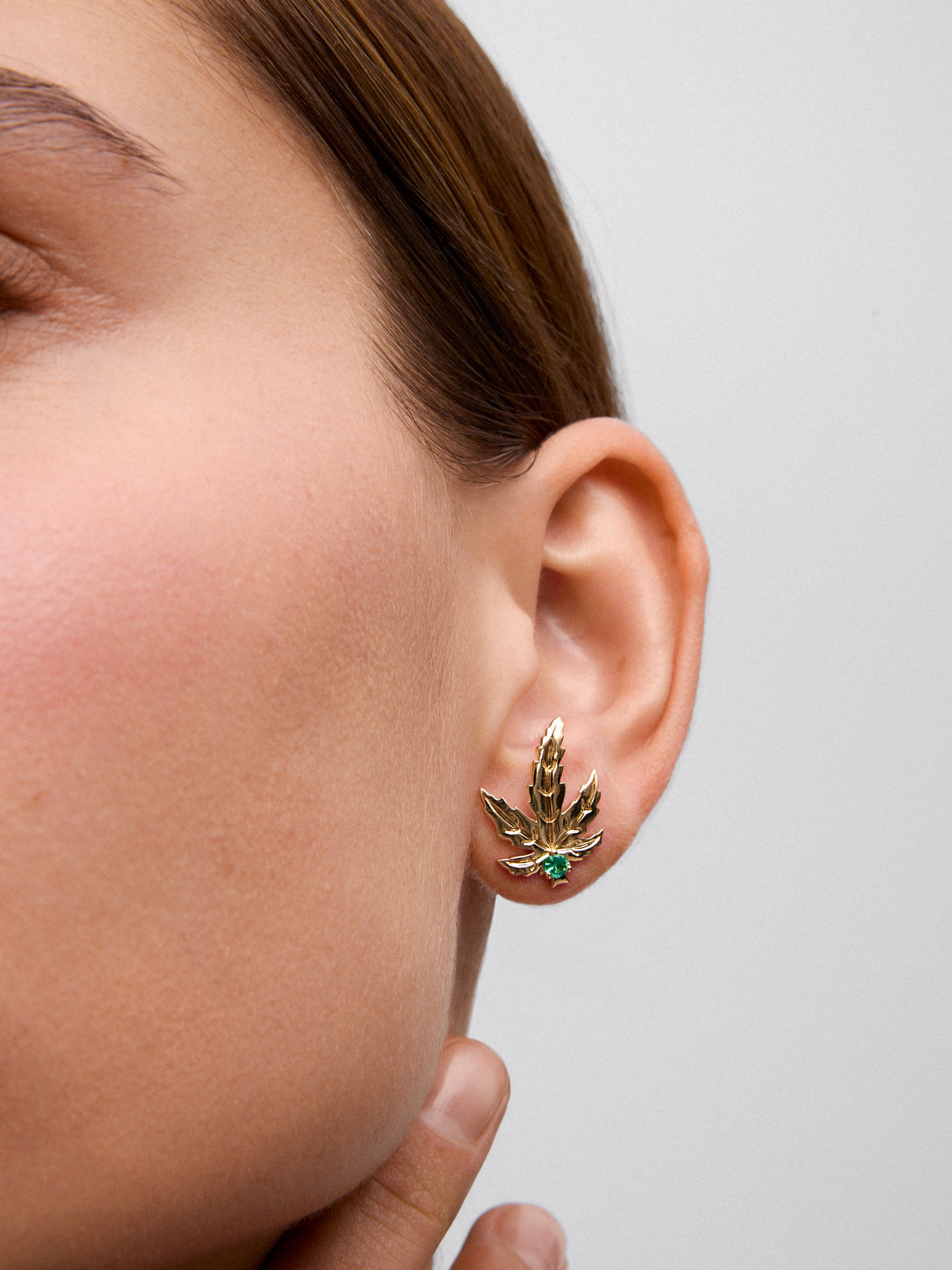 18K yellow gold earrings with two central emeralds totaling 0.15 cts, in a maple leaf design