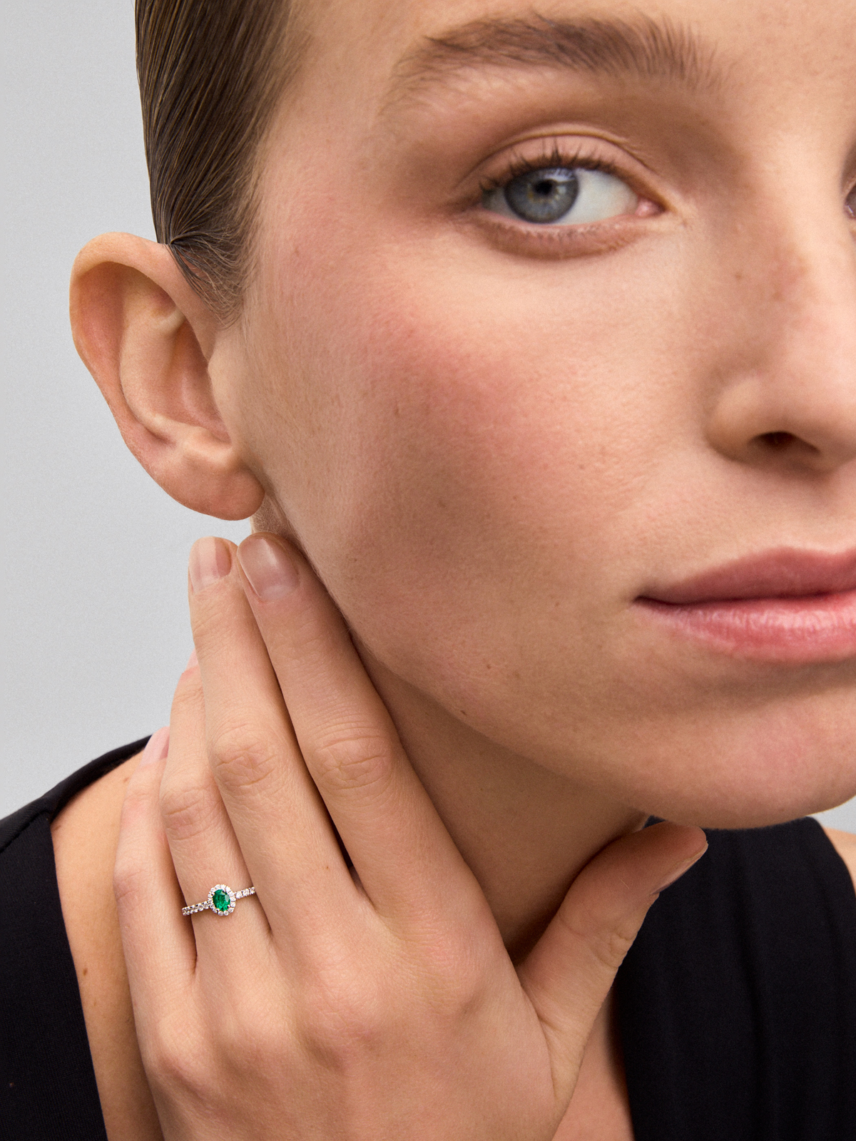 18K white gold ring with a 0.25 ct oval-cut green emerald and brilliant-cut diamond border totaling 0.25 cts