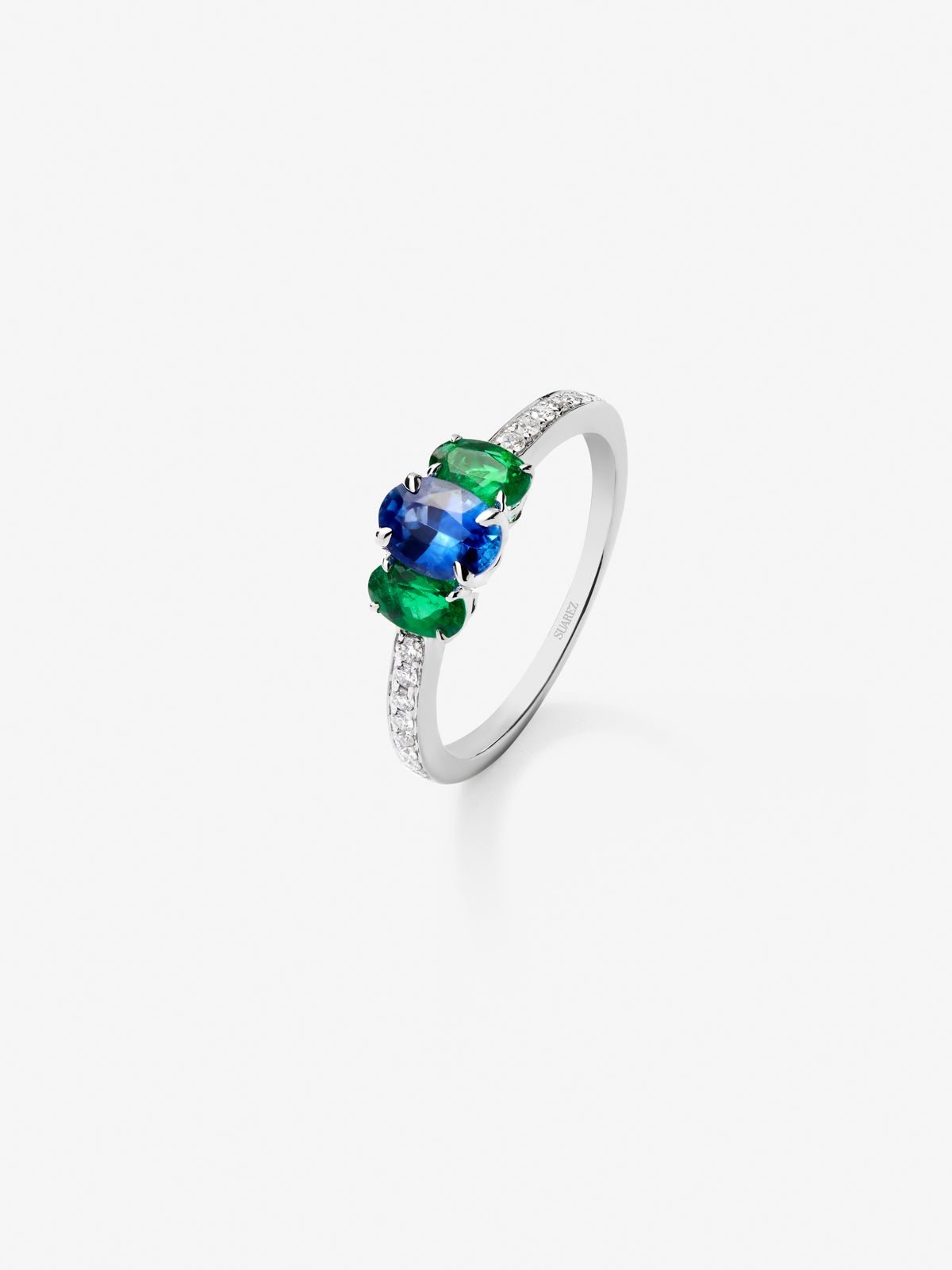 Anillo tresillo de oro blanco de 18K con zafiro azul en talla oval de 0,71 cts, 2 esmeraldas verdes en talla oval con un total de 0,5 cts y 10 diamantes en talla brillante con un total de 0,115 cts