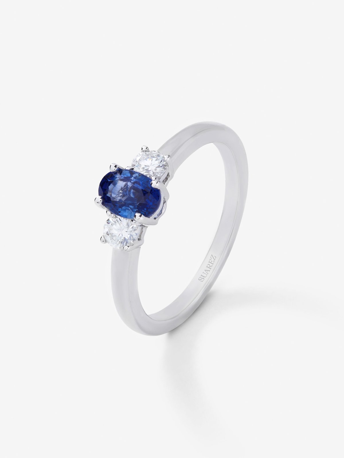 Anillo tresillo de oro blanco de 18K con zafiro azul en talla oval de 0,48 cts y 2 diamantes en talla brillante con un total de 0,24 cts