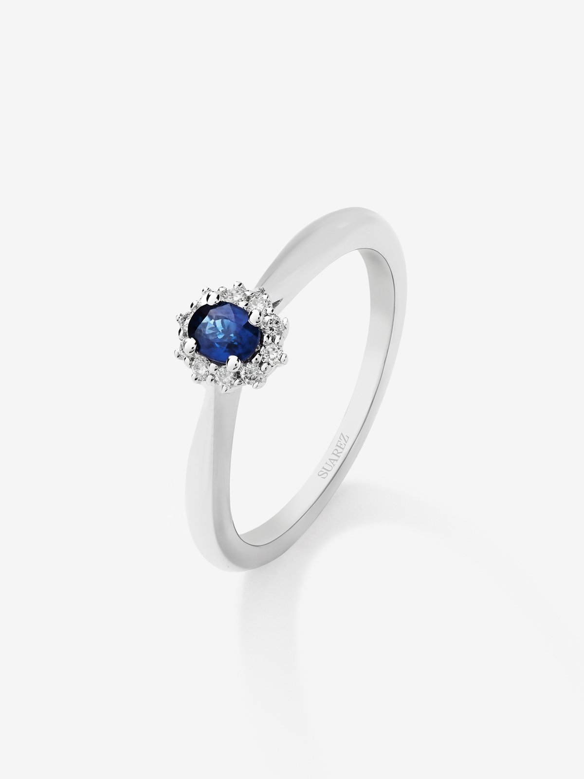Anillo de oro blanco de 18K con zafiro azul en talla oval de 0,22 cts y 10 diamantes en talla brillante con un total de 0,08 cts