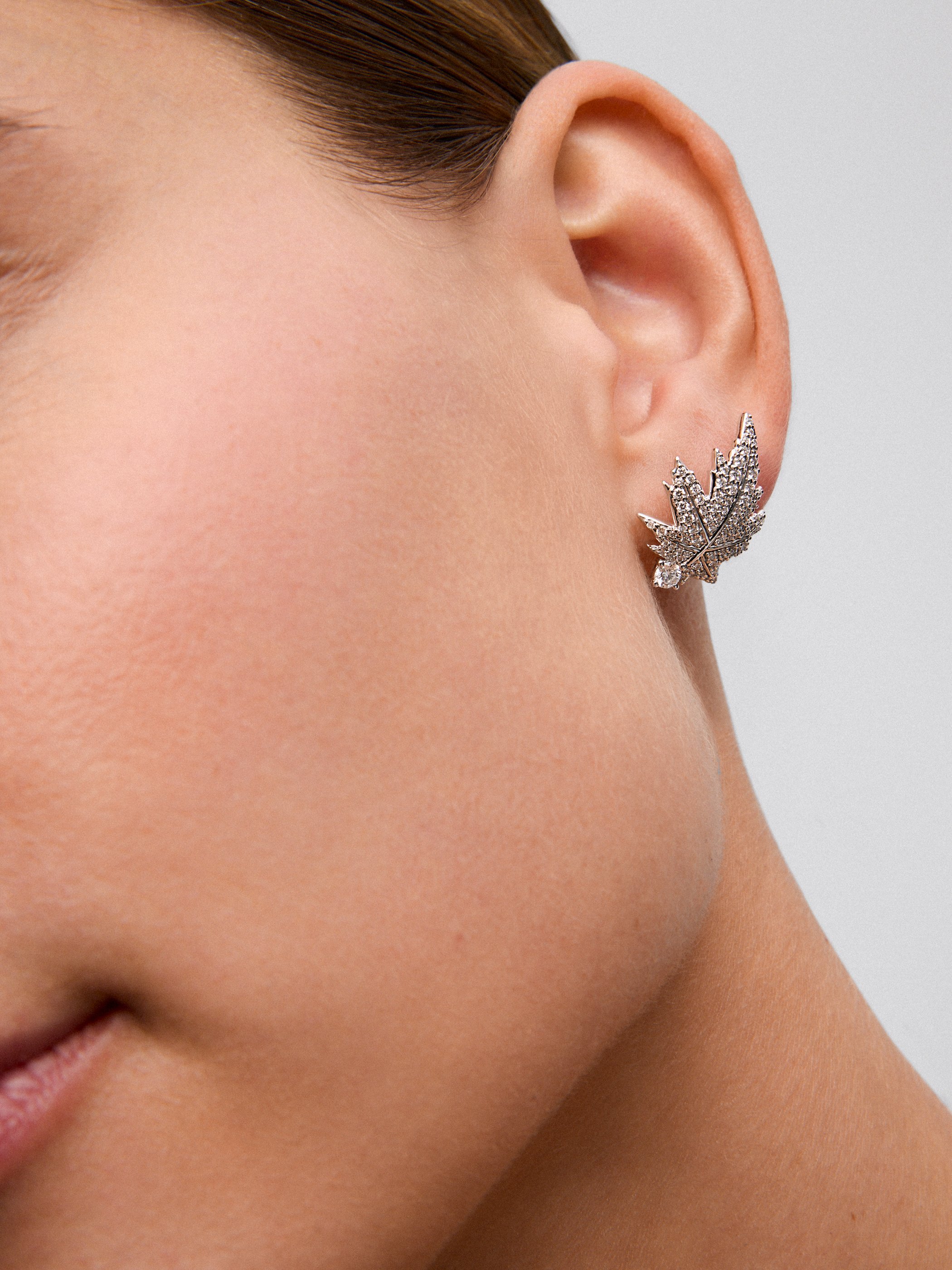 18K white gold earrings with two central diamonds totaling 0.26 cts, diamond pavé, and a maple leaf design.