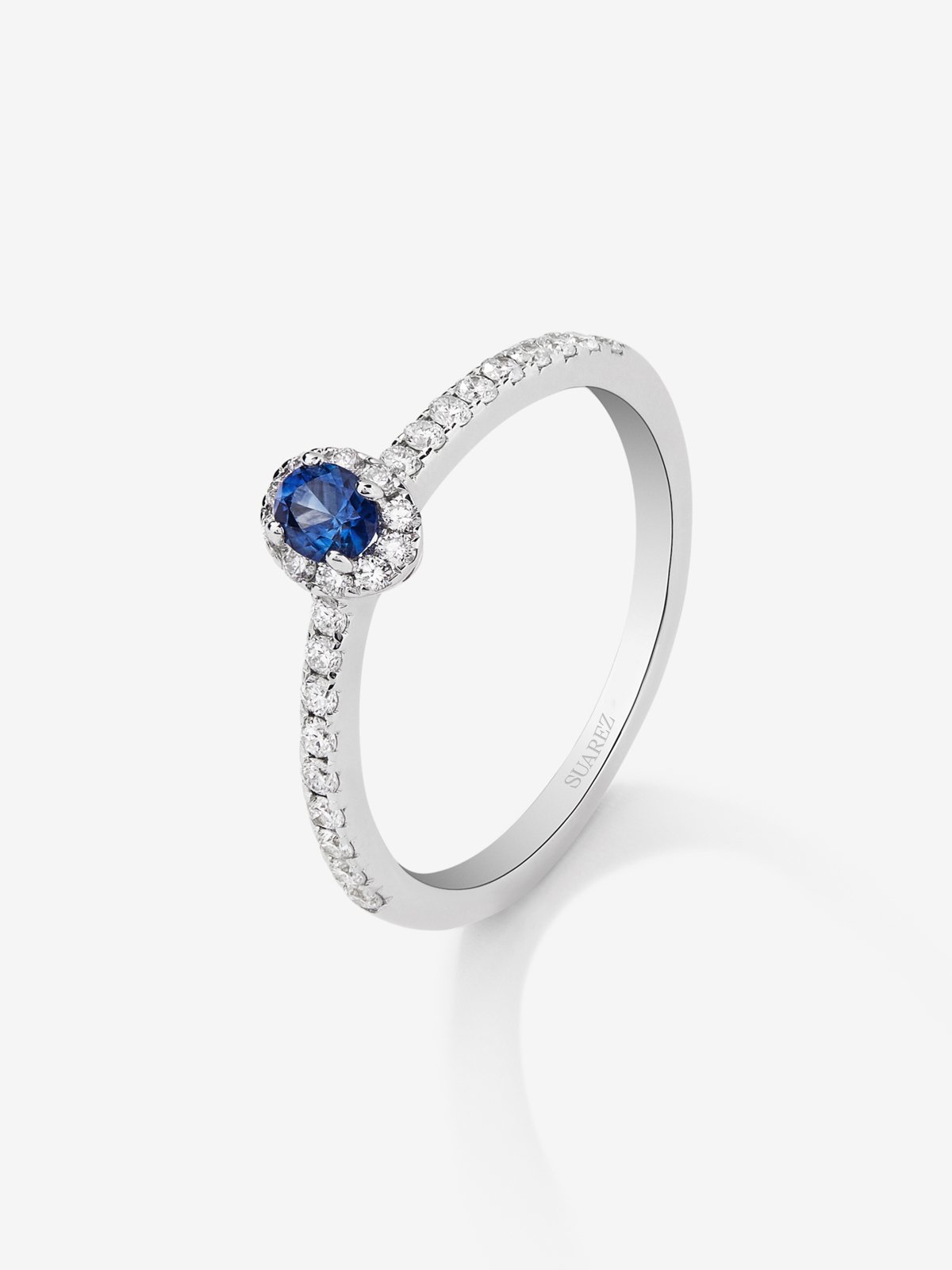 Anillo de oro blanco de 18K con zafiro azul en talla brillante de 0,15 cts y orla y brazo de 28 diamantes en talla brillante con un total de 0,2 cts
